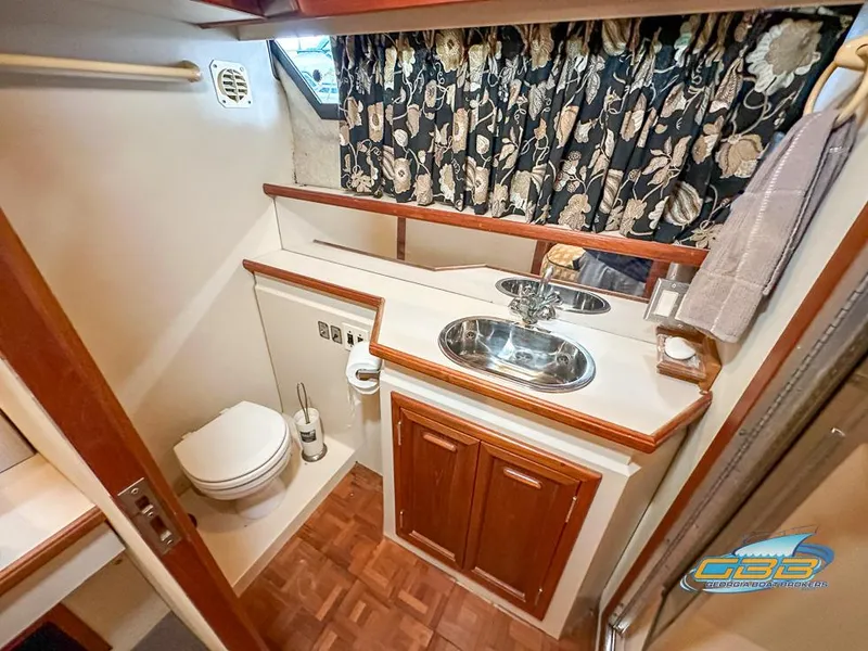 Slide: The Image of 1989 Carver 3807 Aft Cabin bathroom with sink, toilet, and floral curtains. - 41