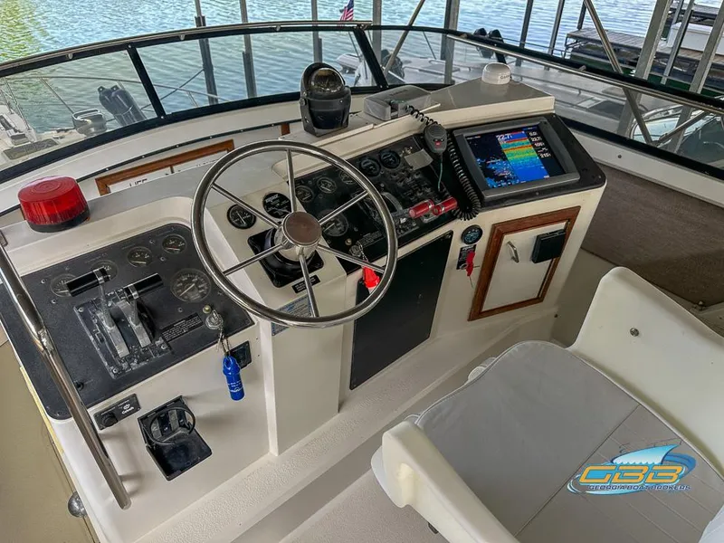 Slide: The Image of 1989 Carver 3807 Aft Cabin helm with steering wheel, controls, and navigation equipment. - 46