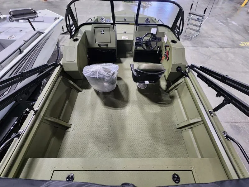Slide: The Image of 2025 SeaArk Protege boat interior with steering console and seating, displayed in a showroom. - 7