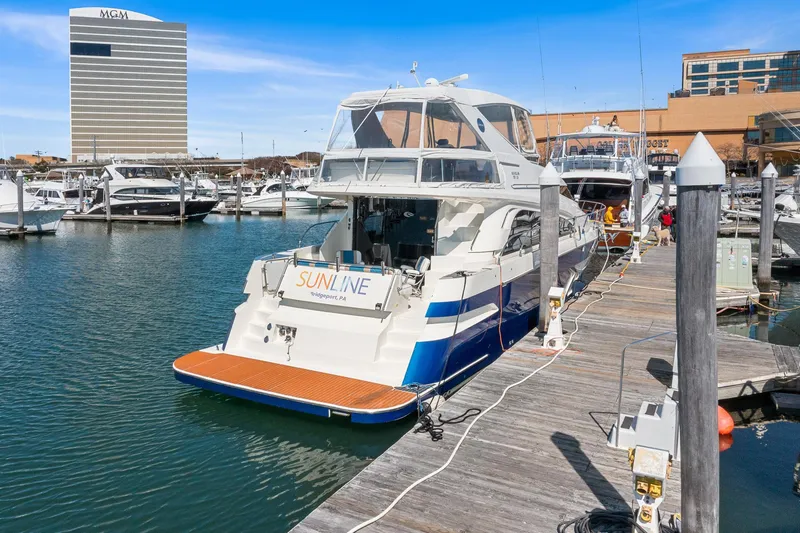 Slide: The Image of 2007 Marquis 55 LS yacht docked at marina with cityscape background. - 2