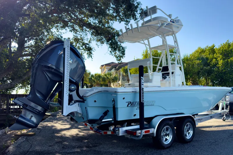 Slide: The Image of 2026 Pathfinder 2500 Hybrid boat on trailer, parked outdoors under trees. - 1