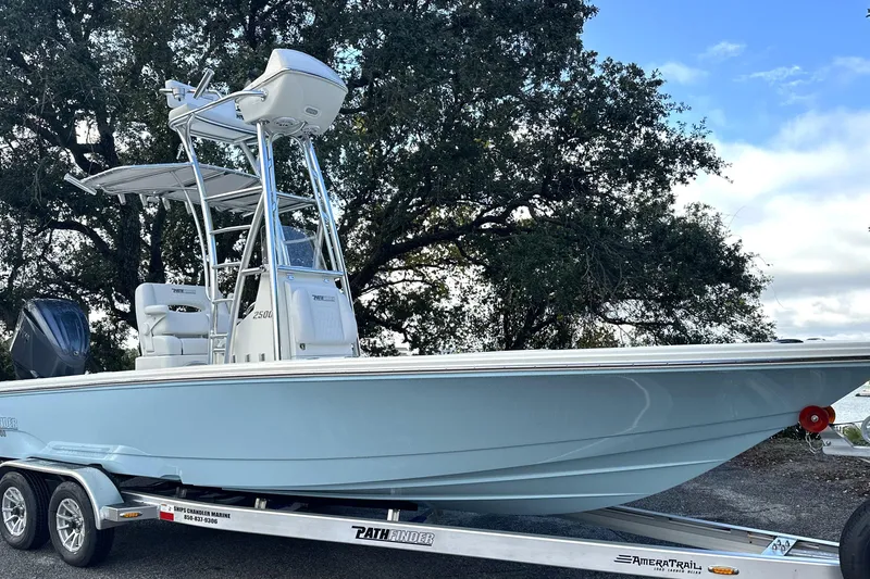 Slide: The Image of 2026 Pathfinder 2500 Hybrid boat on trailer, parked outdoors under a tree. - 25