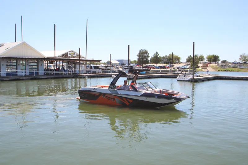 Slide: The Image of 2017 Tigé RZX3 boat on calm water near a marina. - 10