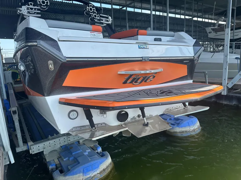 Slide: The Image of 2017 Tigé RZX3 boat with orange accents docked in a marina. - 19