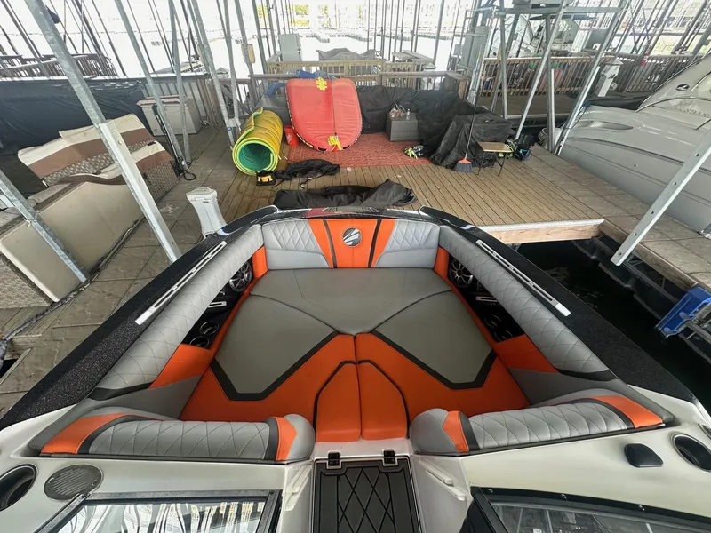 Slide: The Image of 2017 Tigé RZX3 boat interior with orange and gray seating in a dock setting. - 23
