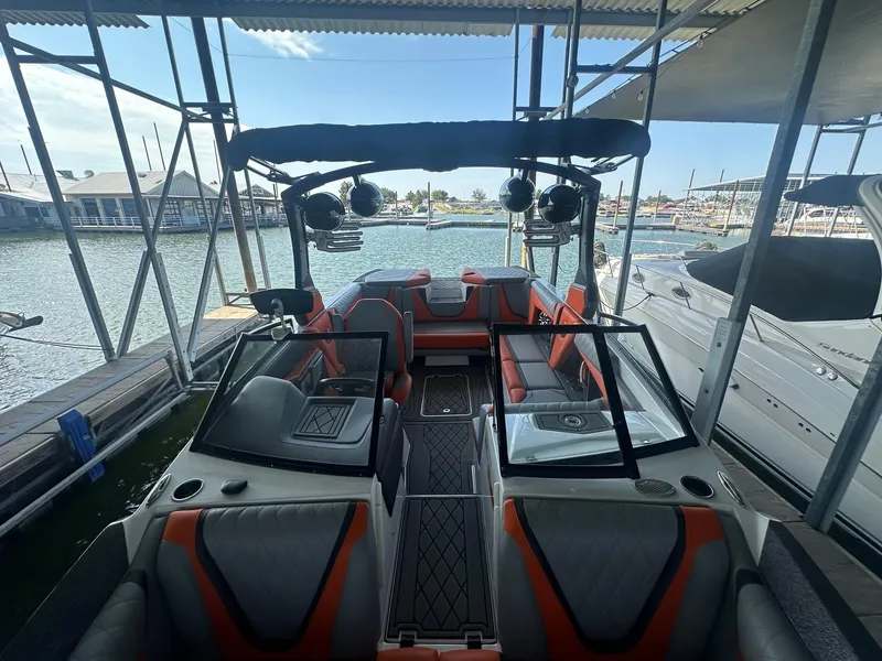Slide: The Image of 2017 Tigé RZX3 boat interior with orange and gray seating, docked in a marina. - 24