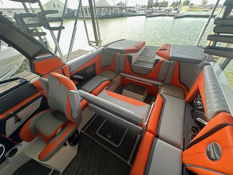 Slide: The Image of 2017 Tigé RZX3 boat interior with orange and gray seating, docked by the water. - 26
