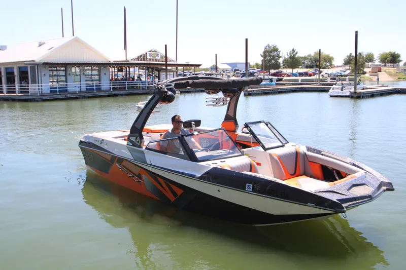 Slide: The Image of 2017 Tigé RZX3 boat on water near a marina, featuring sleek design and vibrant colors. - 4