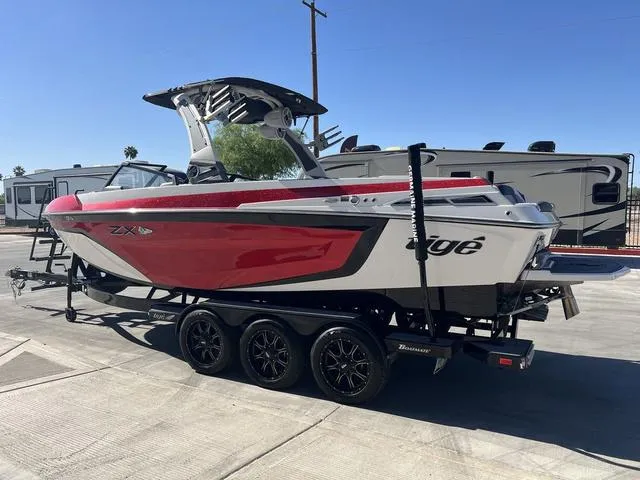 Slide: The Image of 2021 Tigé ZX Class 25 ZX boat on trailer, red and white design, parked outdoors. - 4