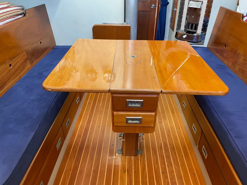 Slide: The Image of 1977 Hinckley Bermuda 40 MK III Sloop interior with wooden table and blue cushioned seating. - 22