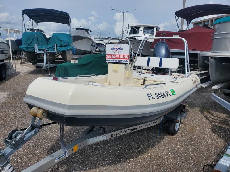 Slide: The Image of 2013 Rigid Boats 12 Sport on trailer in marina, surrounded by other boats. - 1