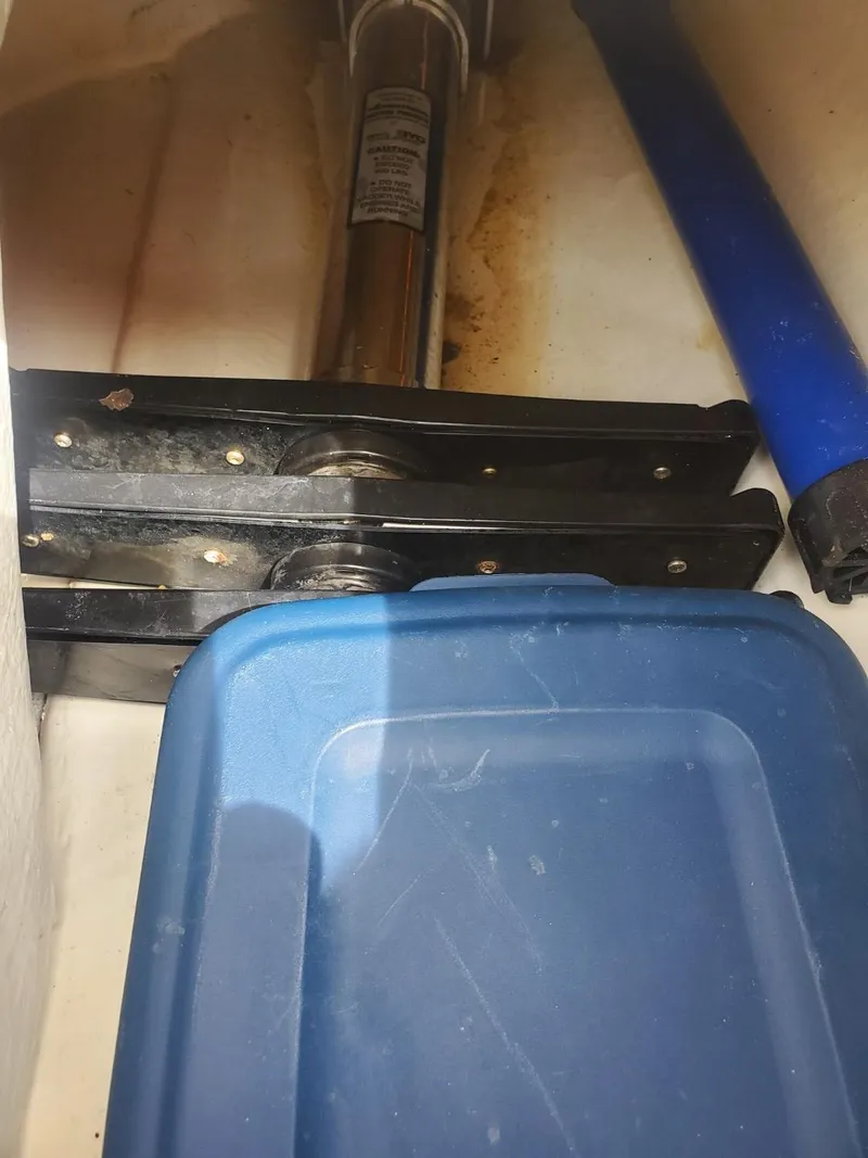 Slide: The Image of Storage compartment in a 2013 Rigid Boats 12 Sport with blue container and metal brackets. - 6