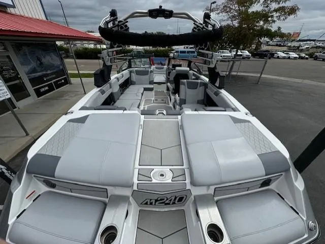 Slide: The Image of 2021 Malibu M240 boat with spacious seating and modern design, parked outdoors. - 10