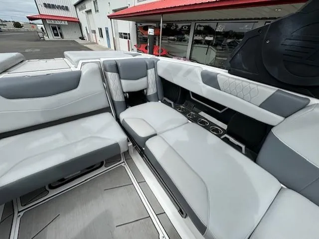 Slide: The Image of 2021 Malibu M240 boat interior with gray and white seating, located near a service center. - 17