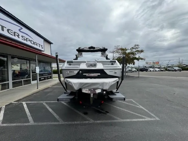 Slide: The Image of 2021 Malibu M240 boat parked outside a dealership under cloudy skies. - 4