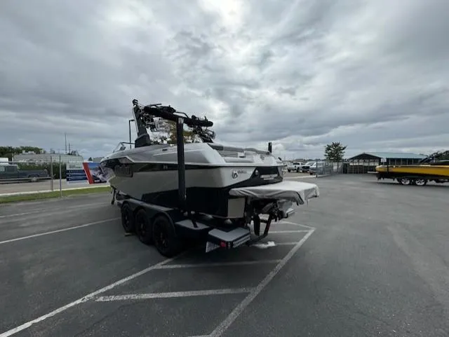 Slide: The Image of 2021 Malibu M240 boat on trailer in parking lot under cloudy sky. - 5