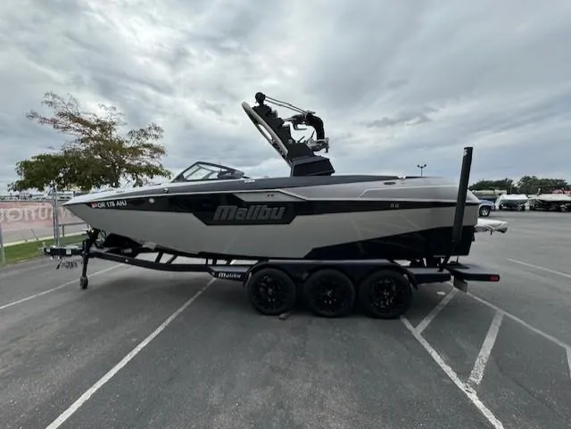 Slide: The Image of 2021 Malibu M240 boat on trailer in parking lot, cloudy sky background. - 6