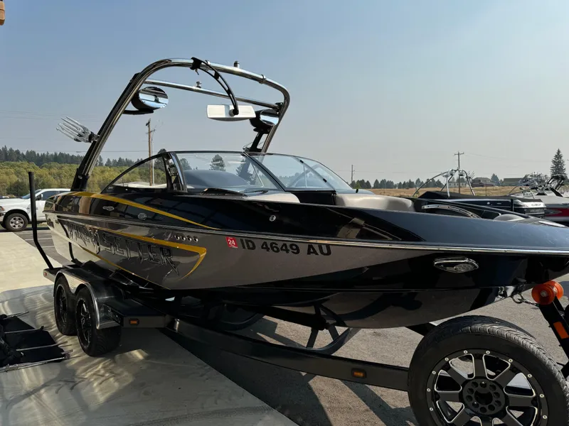 Slide: The Image of 2013 Malibu WVLX boat on trailer, parked outdoors under clear sky. - 4