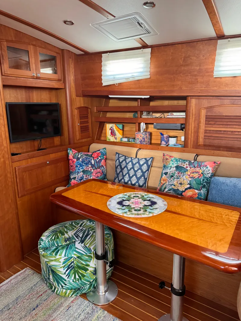 Slide: The Image of 2005 Sabre 38 yacht interior with cozy seating, vibrant cushions, and a polished wooden table. - 7