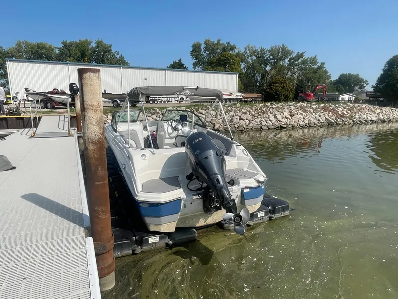 Slide: The Image of 2021 NauticStar 223 DC Deck boat docked at a marina on a sunny day. - 19