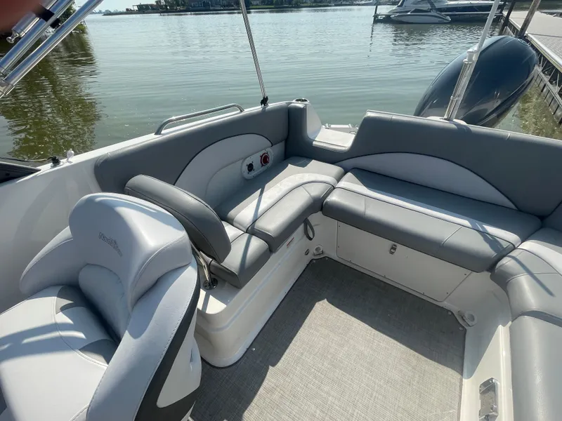Slide: The Image of 2021 NauticStar 223 DC Deck boat interior with gray seating, on calm water. - 7