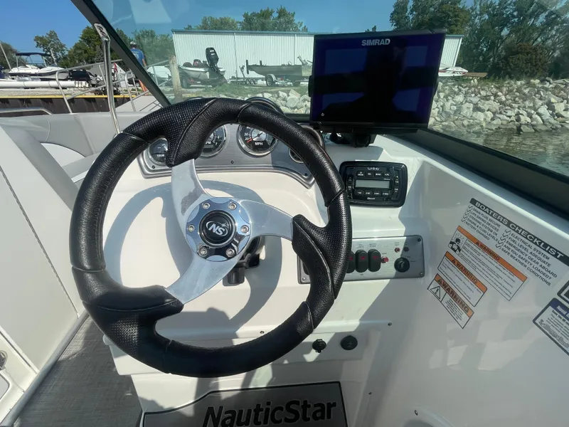 Slide: The Image of 2021 NauticStar 223 DC Deck boat helm with steering wheel and navigation system. - 9