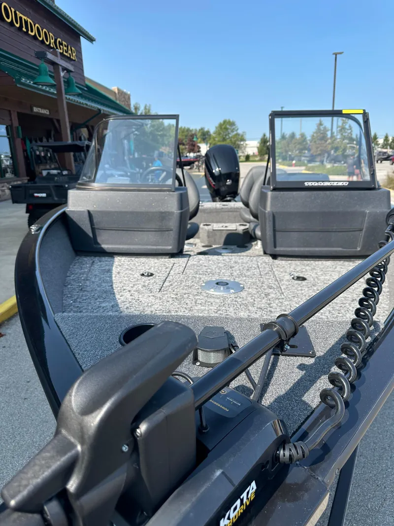 Slide: The Image of 2025 Tracker Pro Guide V-175 WT boat with dual windshields, parked outdoors. - 2