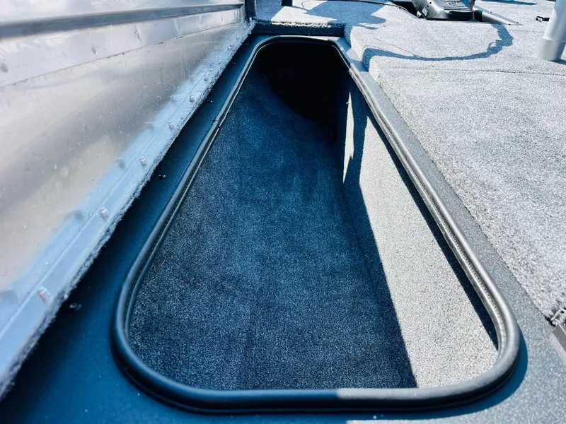 Slide: The Image of 2025 Tracker Pro Team 175 boat storage compartment with carpeted interior. - 13