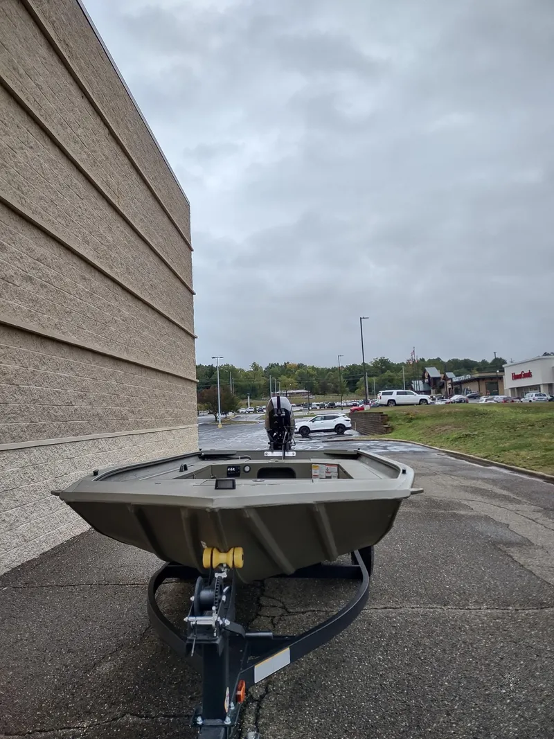 Slide: The Image of 2025 Tracker Grizzly 1654 T Sportsman boat on trailer, parked outdoors. - 2