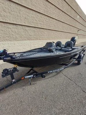 Slide: The Image of 2025 Tracker Super Guide V-16 SC fishing boat on trailer, parked outdoors. - 2