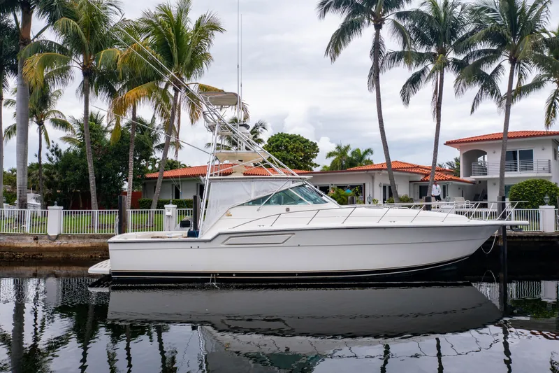 Slide: The Image of 1995 Tiara Yachts 4300 Open docked by palm trees and waterfront homes. - 1