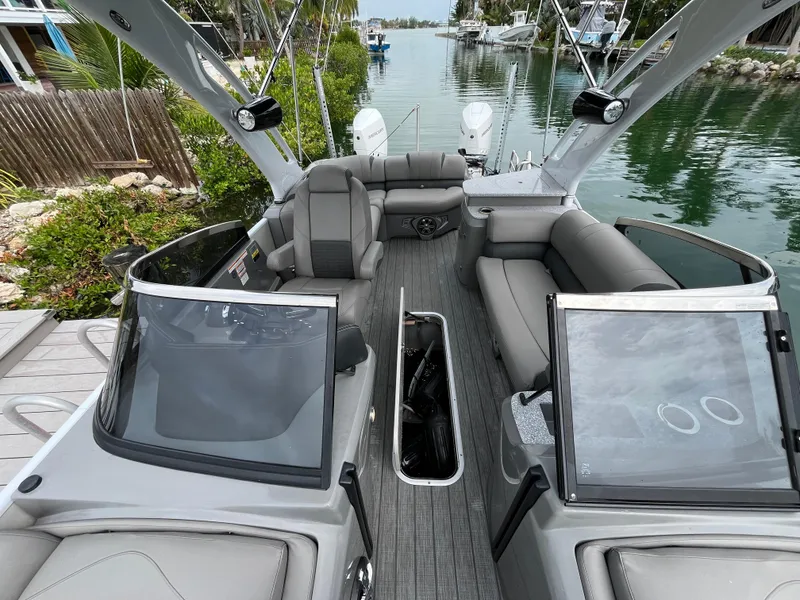 Slide: The Image of 2021 Tahoe Grand Tahoe ELW boat interior with luxurious seating and sleek design on a calm waterway. - 27