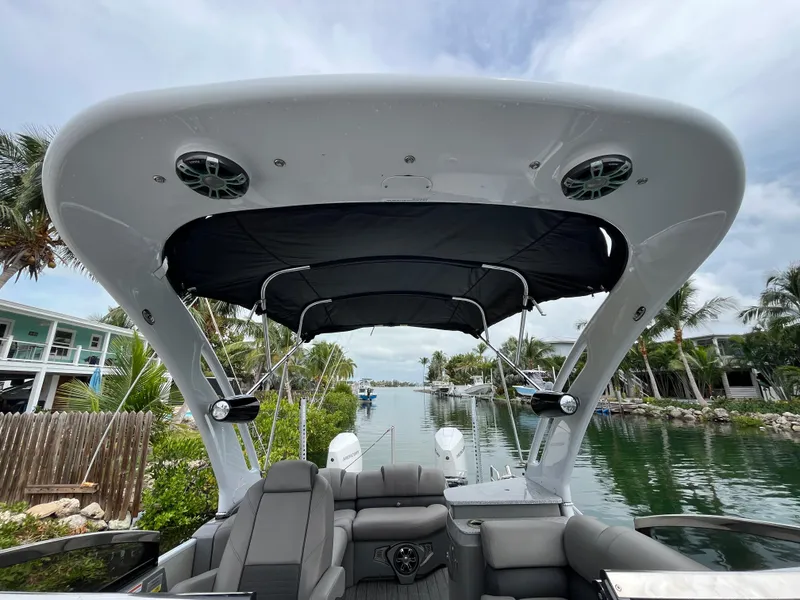 Slide: The Image of 2021 Tahoe Grand Tahoe ELW boat with canopy, docked by a scenic waterfront. - 29