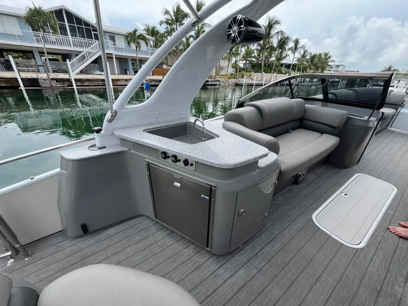 Slide: The Image of 2021 Tahoe Grand Tahoe ELW boat interior with seating, sink, and storage, docked by waterfront homes. - 38