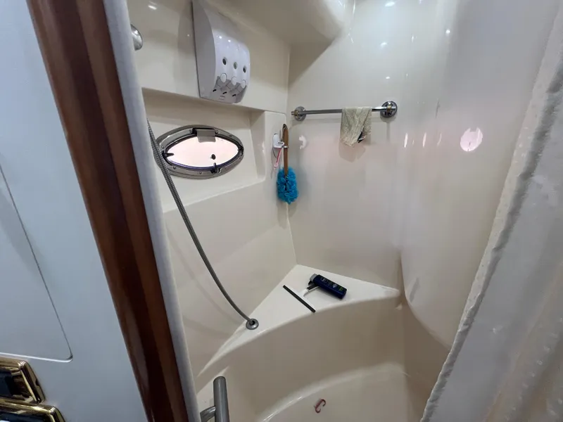 Slide: The Image of 2001 Carver 530 VOYAGER yacht bathroom with shower, towel rack, and porthole window. - 13