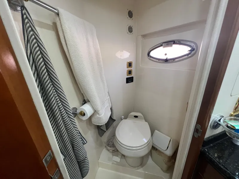 Slide: The Image of Compact bathroom in 2001 Carver 530 Voyager yacht with toilet, towel, and porthole window. - 14