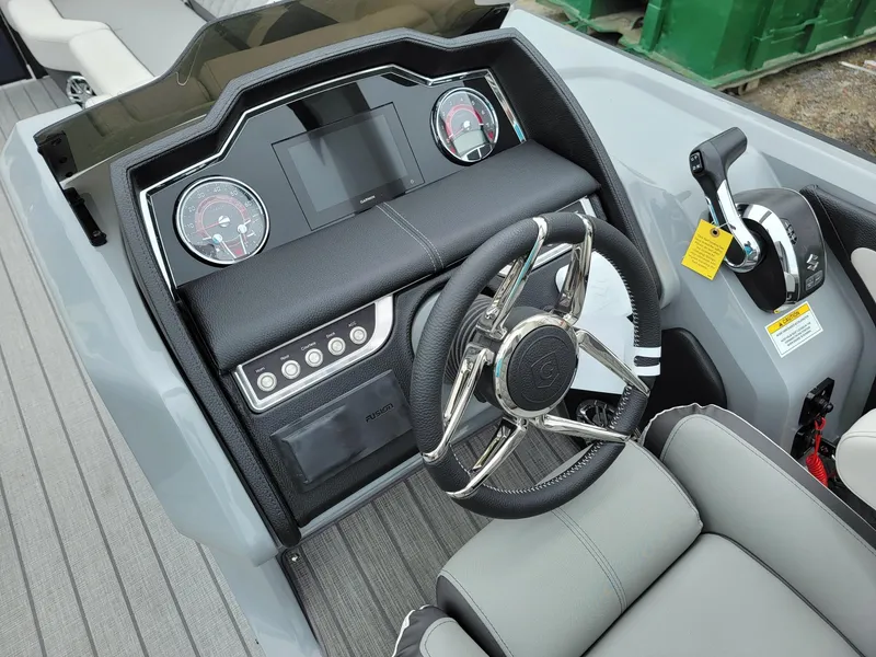 Slide: The Image of 2025 Godfrey AquaPatio 255 ULC boat dashboard with steering wheel and control panel. - 12