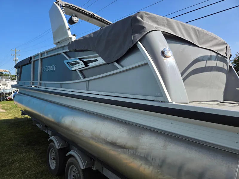Slide: The Image of 2025 Godfrey AquaPatio 255 ULC pontoon boat with cover, parked on trailer. - 5