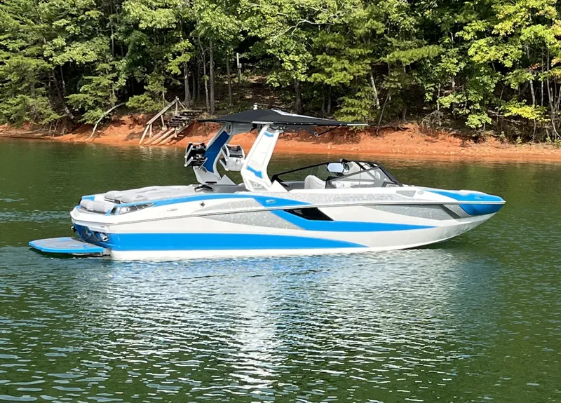 Slide: The Image of 2025 Centurion Fe23 boat on a serene lake with lush forest backdrop. - 1