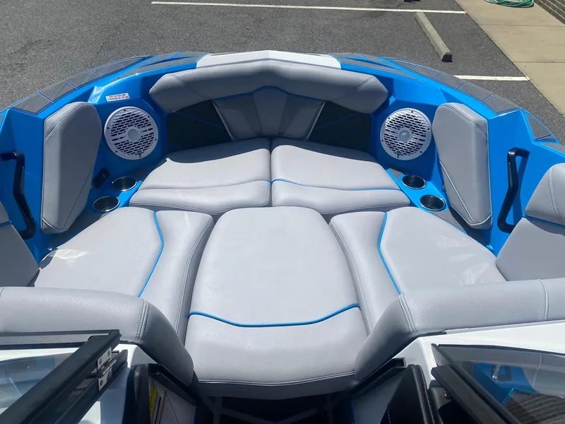 Slide: The Image of 2025 Centurion Fe23 boat interior with blue and gray seating, speakers, and cup holders. - 13