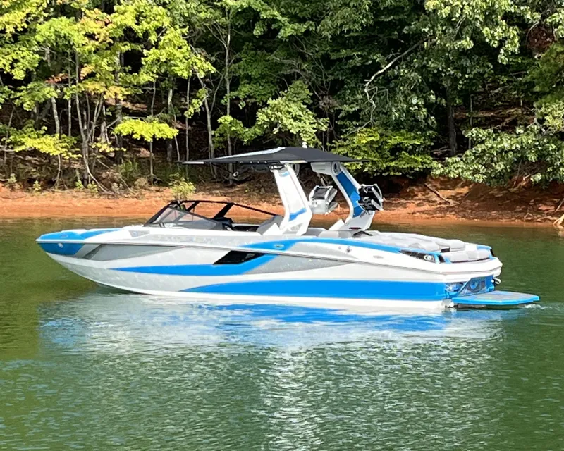 Slide: The Image of 2025 Centurion Fe23 boat on a serene lake with lush green forest backdrop. - 4