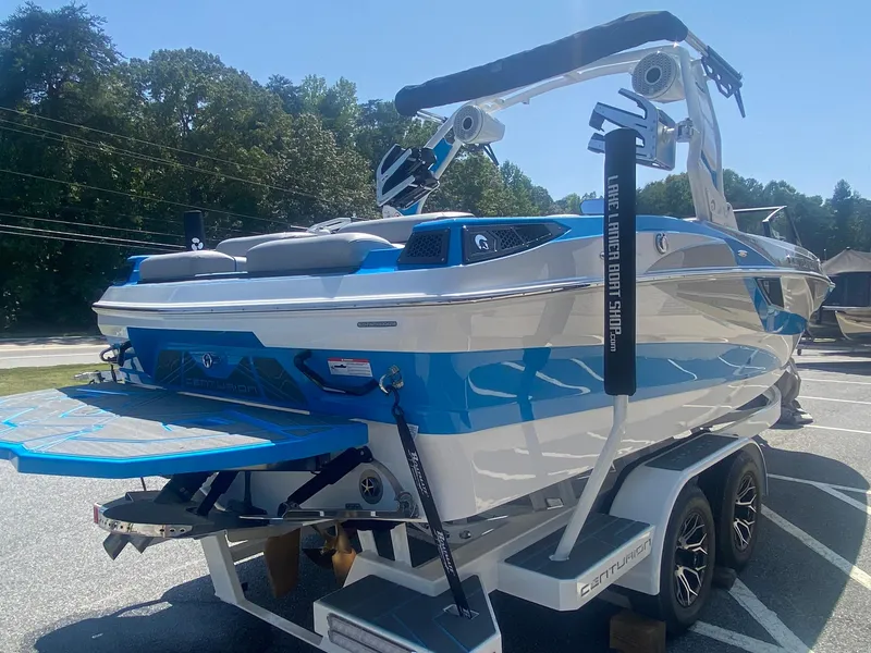 Slide: The Image of 2025 Centurion Fe23 boat on trailer, blue and white design, parked outdoors. - 8