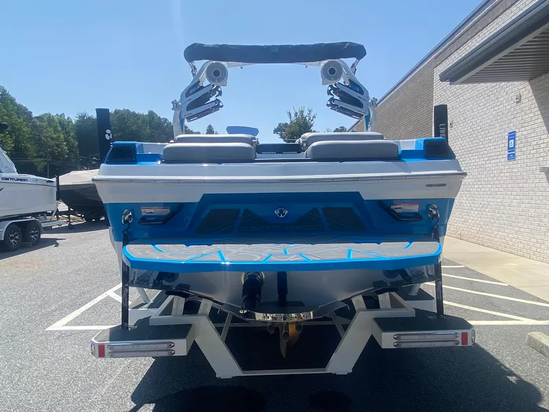 Slide: The Image of 2025 Centurion Fe23 boat, blue and white, parked outdoors, rear view. - 9