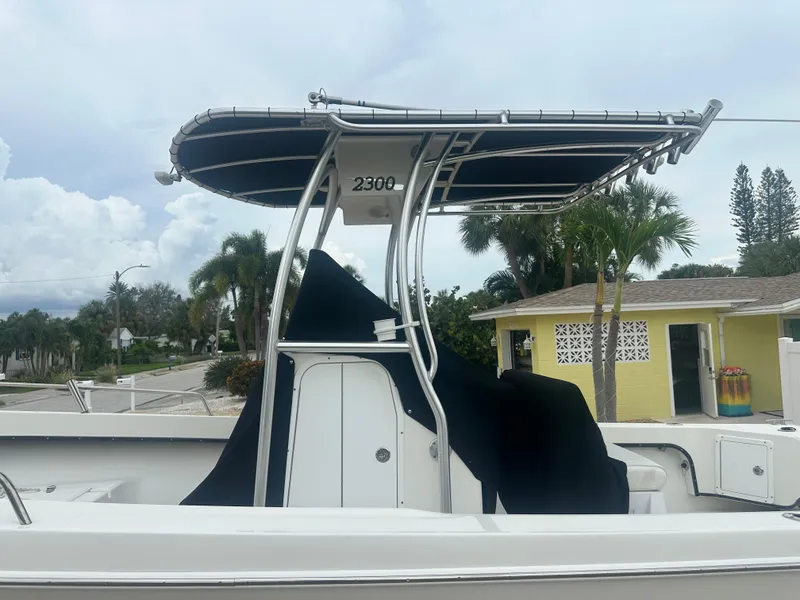 Slide: The Image of 2017 May-Craft 2300CCX boat with T-top, parked near a yellow house. - 16