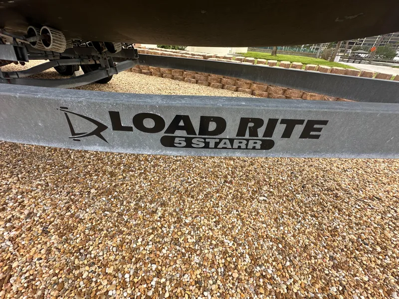 Slide: The Image of Load Rite 5 Starr trailer for 2017 May-Craft 2300CCX boat on gravel surface. - 47