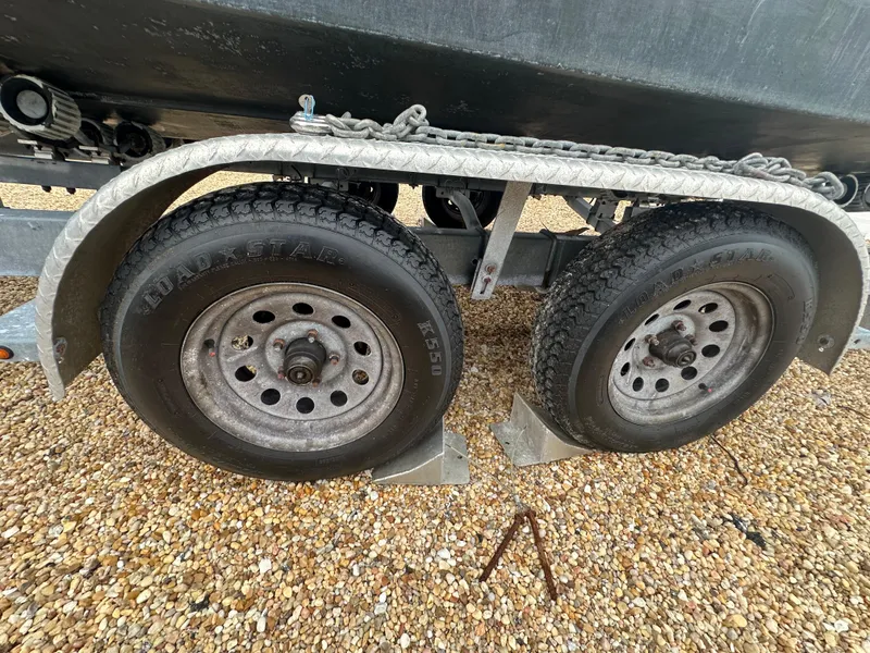Slide: The Image of Trailer wheels of a 2017 May-Craft 2300CCX boat on gravel surface. - 49