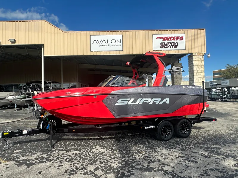 The Image of 2025 Supra SA 450 boat in vibrant red, parked outside a dealership. - 0