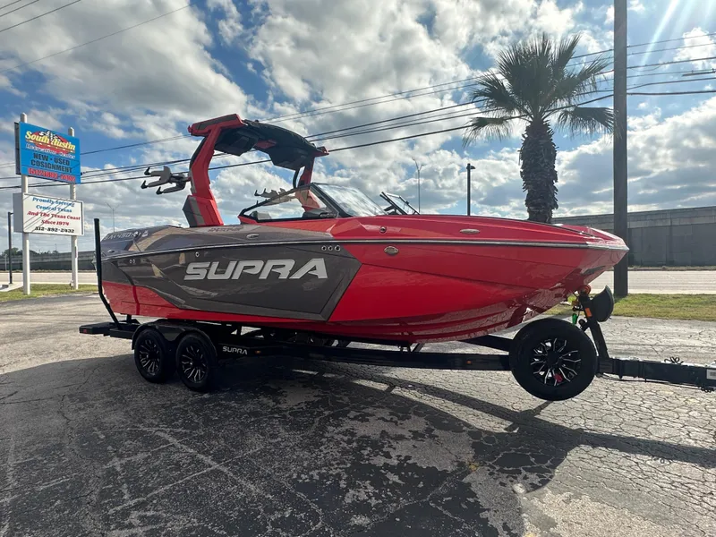 Slide: The Image of 2025 Supra SA 450 boat in vibrant red on a trailer, parked outdoors. - 3