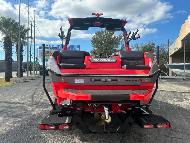 Slide: The Image of 2025 Supra SA 450 boat, red and black, parked outdoors under a blue sky. - 6