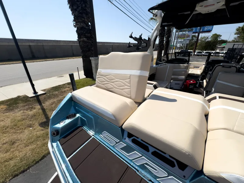 Slide: The Image of 2025 Supra SL 550 boat with beige seating and blue accents, parked outdoors. - 14